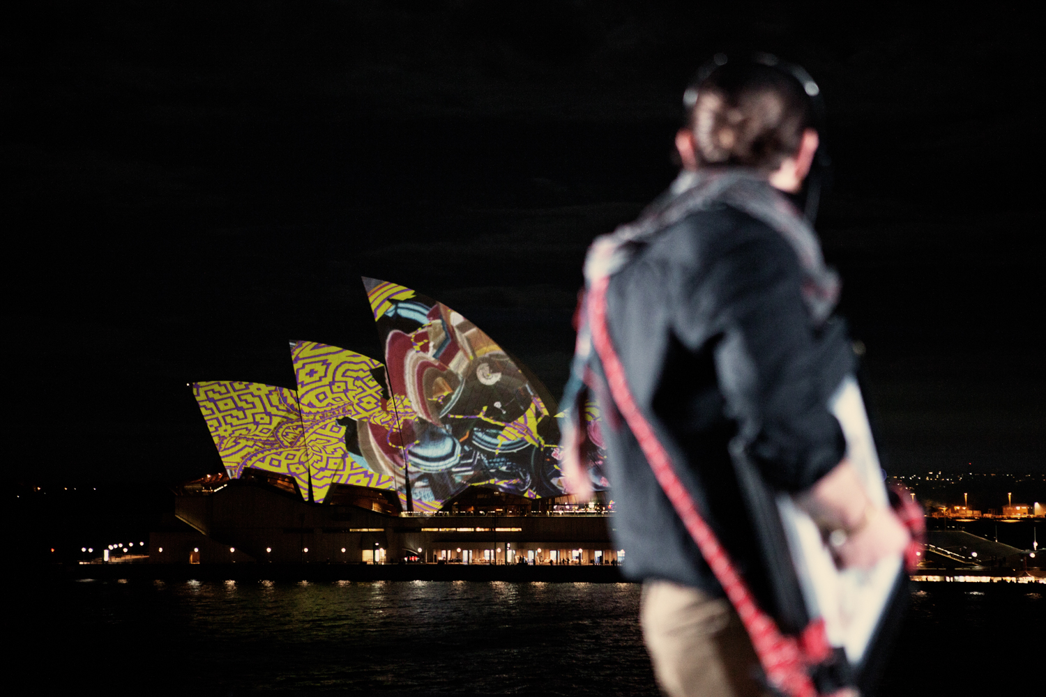 A night shot of the Sydney Opera House, illuminated by colourful lights by Mario Zmudzinski at Magnum Studio