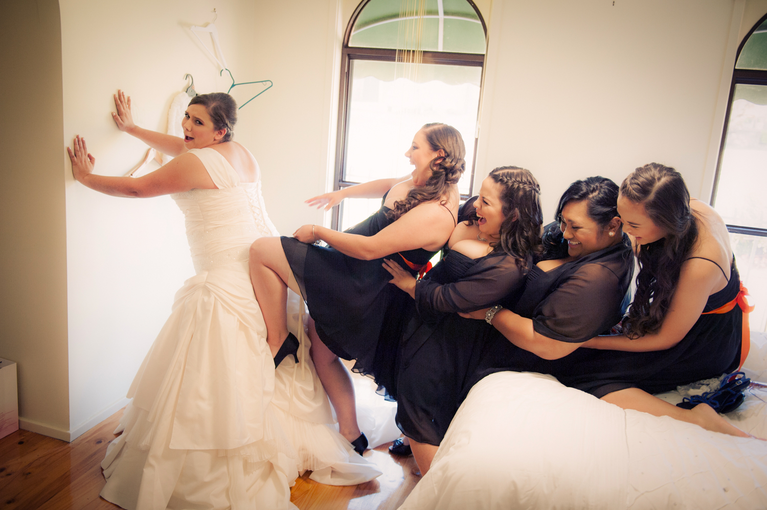 A bride putting on her wedding dress with the help of her bridesmaids