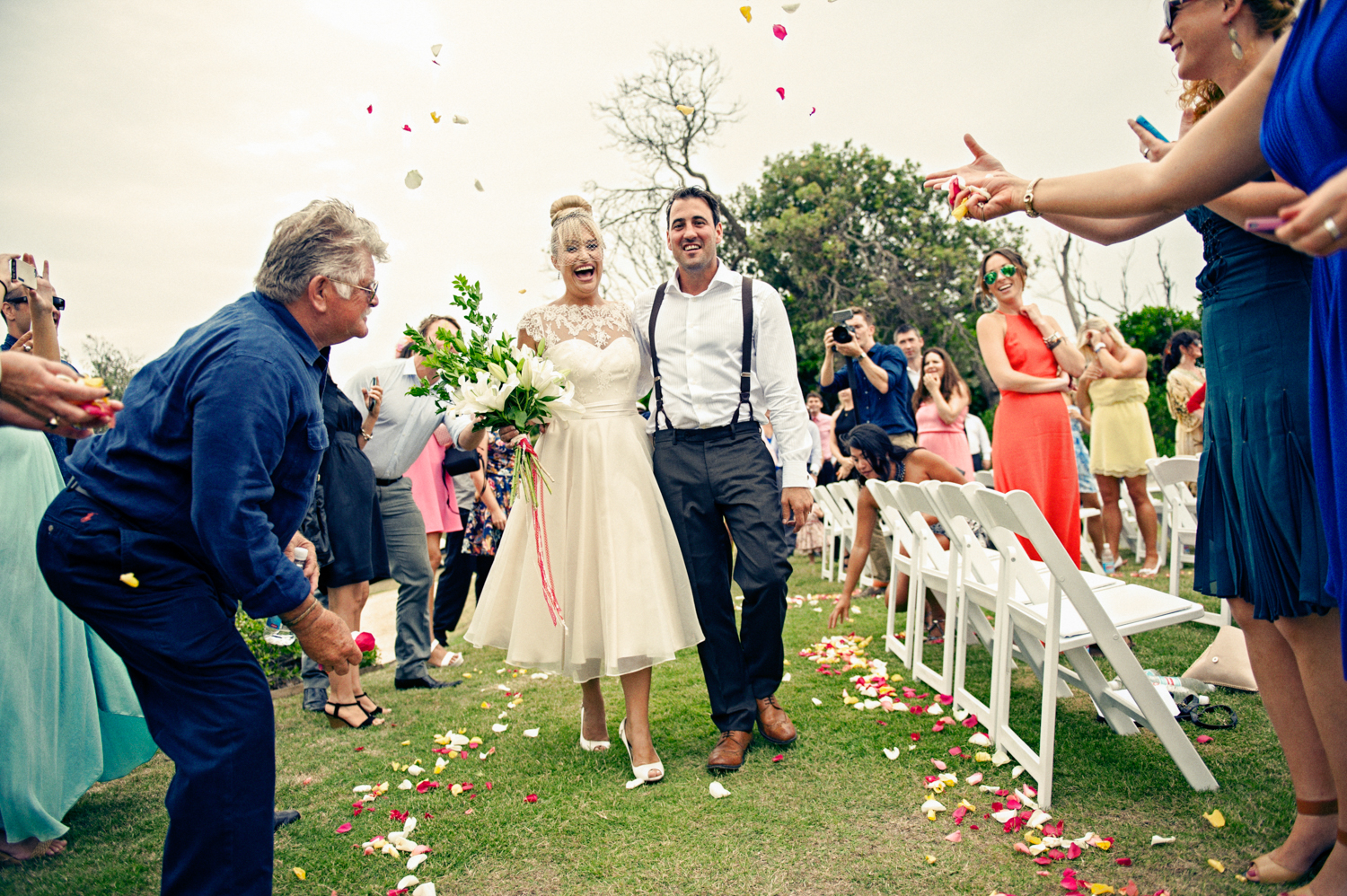A joyful moment captured as bride, groom and guests throw flowers at the wedding.