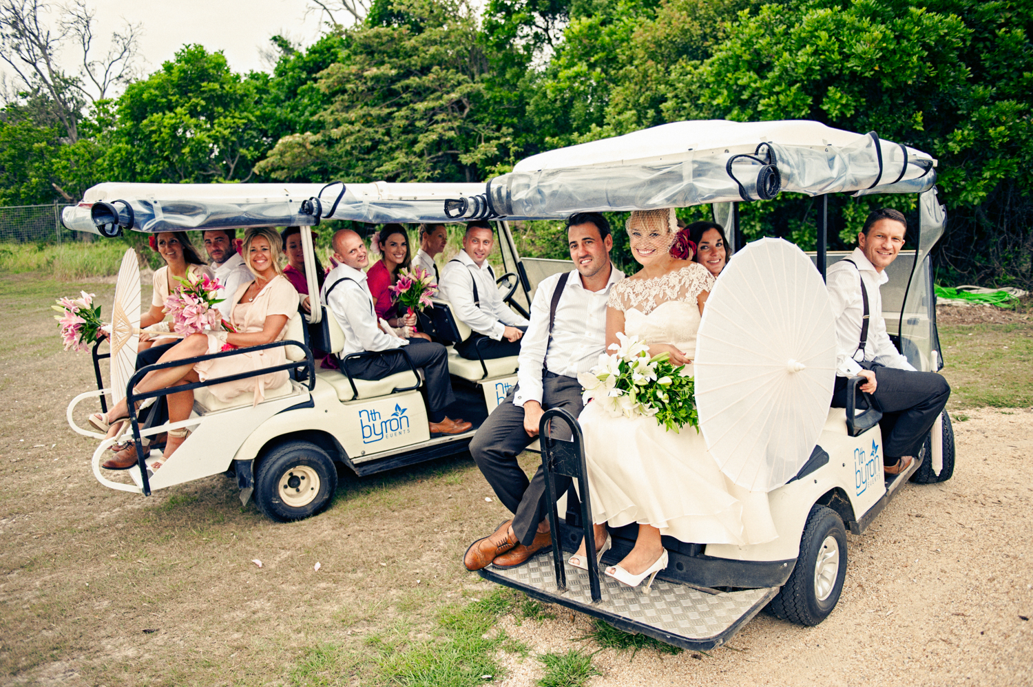 Bride and groom with friends joyfully driving a golf cart on their wedding day