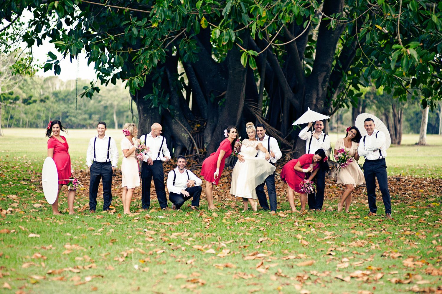 Wedding couple with friends having fun under a big tree in the countryside
