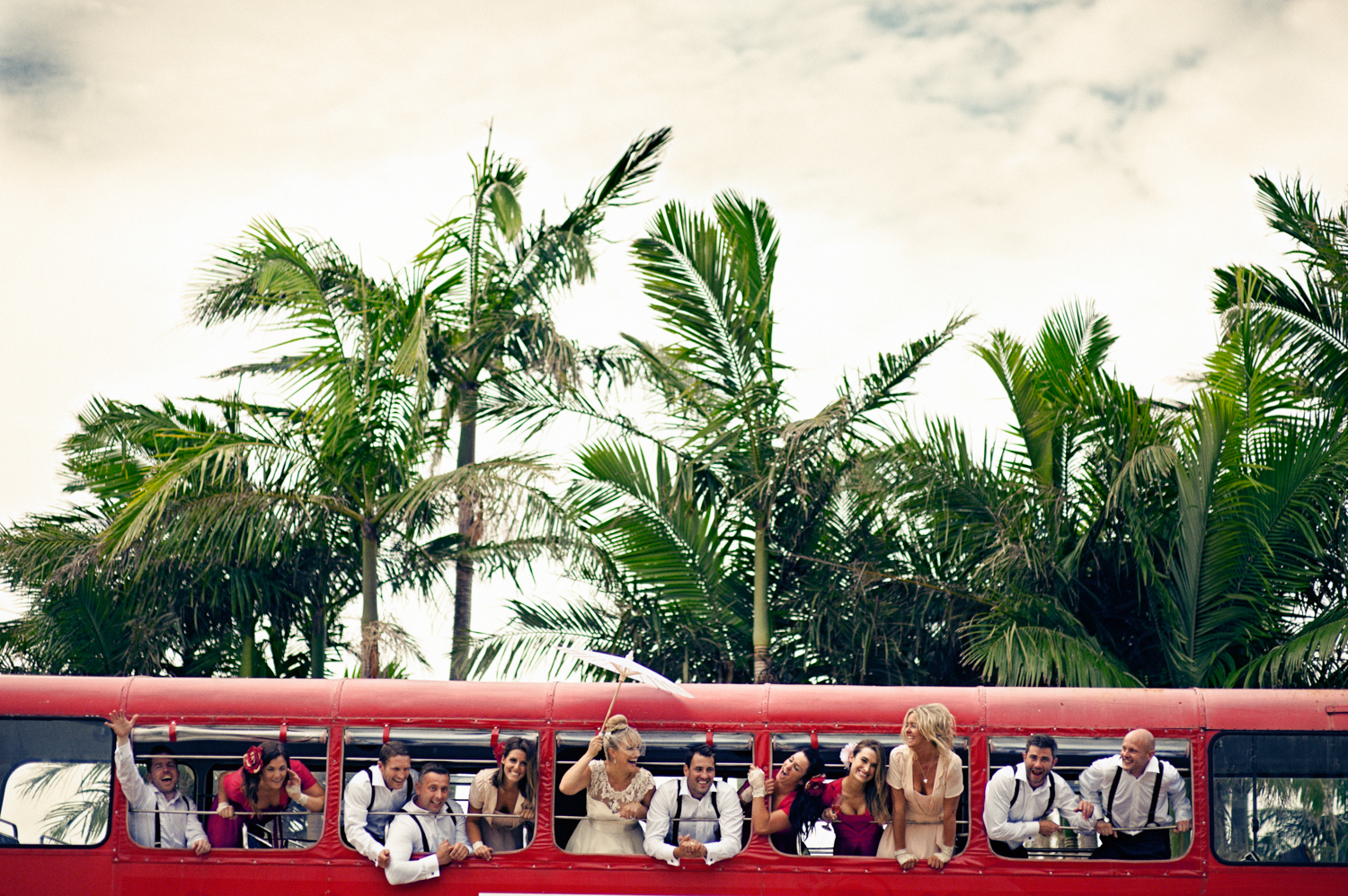 Wedding guests celebrating on a vintage London bus with the bride and groom