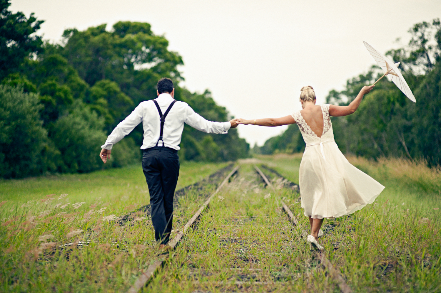 Newlyweds enjoying a romantic walk on a vintage train track