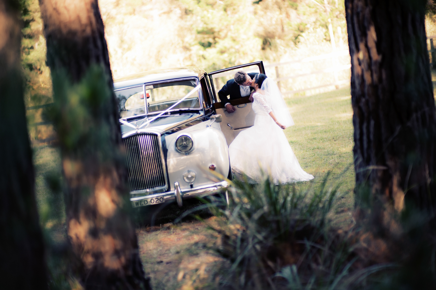 A bride and groom posing in a vintage car, photographed by Mario Zmudzinski from Magnum Studio